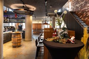 Eingangsbereich mit weihnachtlicher Dekoration, Stehtisch und Blick auf die Bar.